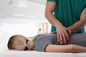 A patient discusses spinal treatment risks with a clinician in a bright examination room.