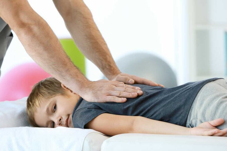 Person walking on a sidewalk while a clinician observes foot placement and lower-body alignment.