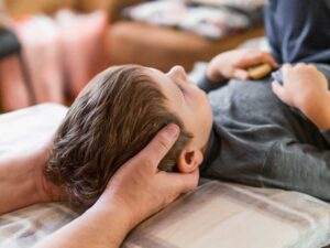 Adult discussing back pain with a chiropractor in a bright, neutral examination room.