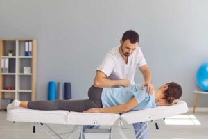 Person discussing neck tension with a chiropractor in a bright treatment room.