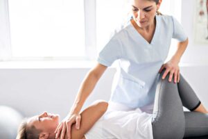 Adult sitting safely on a treatment table while a clinician checks neck movement and balance symptoms