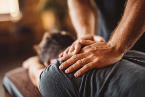 Person resting with a warm compress on the lower back after a chiropractic adjustment.