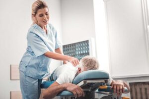 Adult receiving guided back exercises beside a treatment table in a bright clinical room.