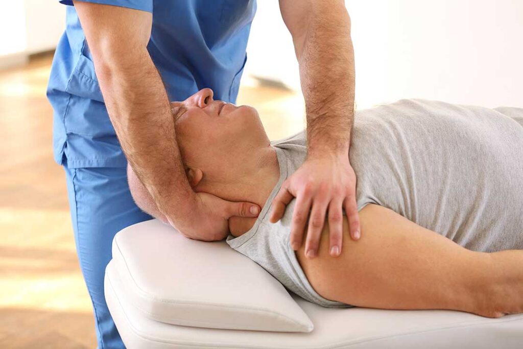 Person gently rotating a shoulder while seated in a bright home setting, with the upper arm and shoulder clearly visible.