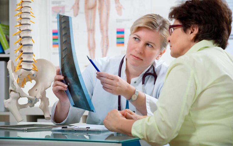 Parent discusses a child’s back discomfort with a health professional in a bright examination room.